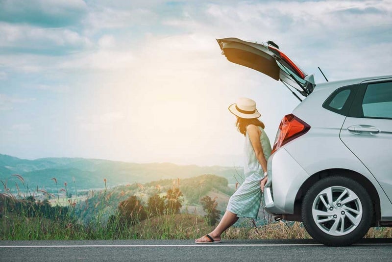 Woman in hatchback looking over mountain range