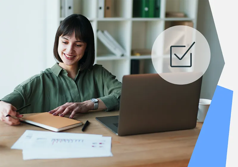Desk with laptop, notebook, papers, and checkmark icon overlay