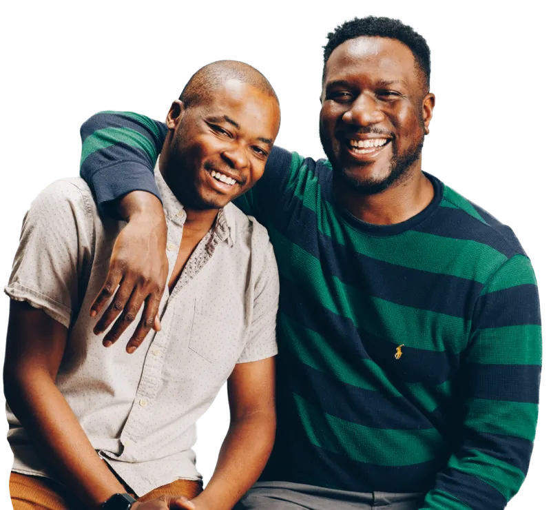 Two men sitting beside each other smiling. 