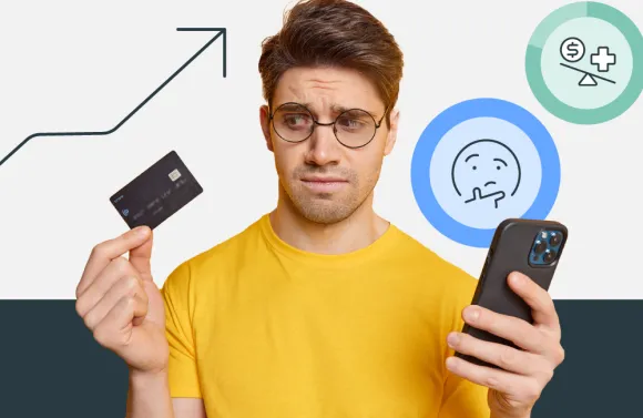 A  man in a yellow shirt, holding an Health Savings Account debit card in his right hand, and his phone in his left hand. He looks confused. 