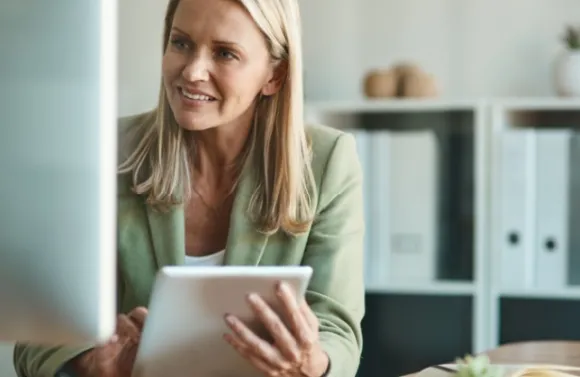 Smiling businesswoman looking at computer, holding a tablet