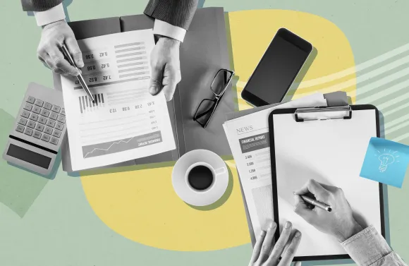 Top view of hands working with documents, clipboard, calculator, phone, and coffee on a desk.