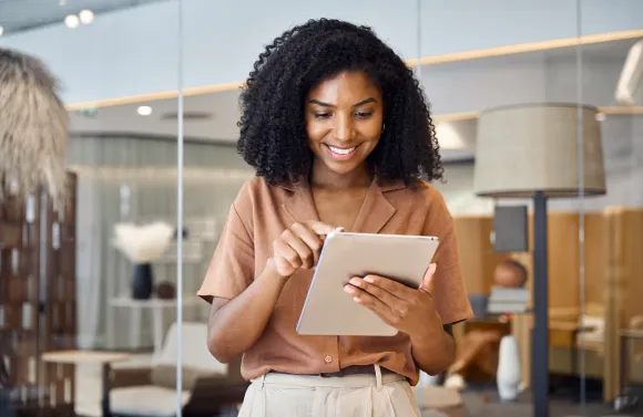 Person standing in a modern office, using a tablet with both hands.