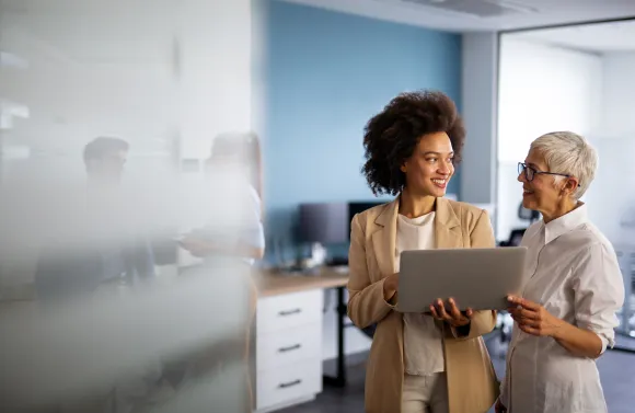 HR professional reviewing employee benefits enrollment communications on a laptop, preparing for passive open enrollment season