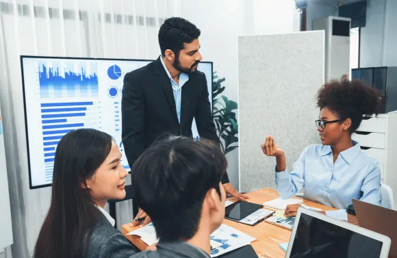 Business team reviews charts on a screen while discussing data-driven benefits strategy in a meeting.