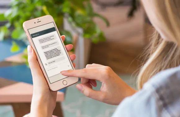 Person using a smartphone to interact with the Benefitfocus chatbot.