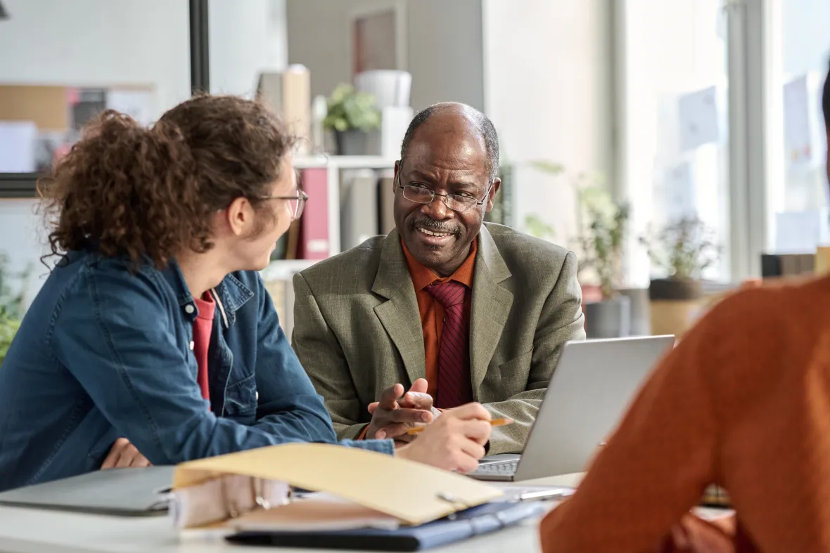 Portrait of smiling senior man talking to young colleague in business meeting